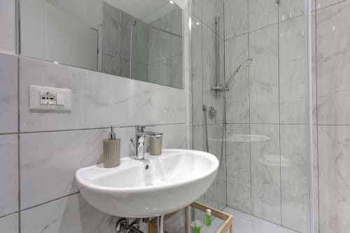 Modern bathroom in Sleep tight Florence B&B featuring white basin sink, marble-tiled shower enclosure, and chrome fixtures
