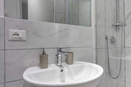 Modern bathroom sink with marble tiles at Sleep tight Florence BnB in Firenze, shower visible