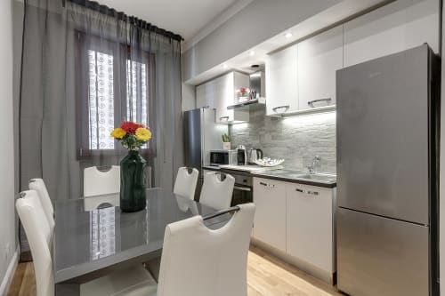 Modern kitchen with white cabinets, stainless steel appliances, dining table with flowers at Sleep tight Florence B&B in