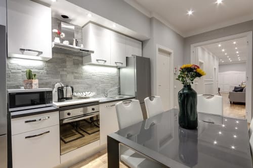 Modern kitchen in Sleep tight Florence standard room with white cabinetry, gray backtile, stainless steel appliances, and