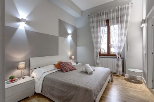 Camera moderna al Sleep tight Florence B&B a Firenze con letto bianco, biancheria grigia, pavimenti in legno e luce naturale da