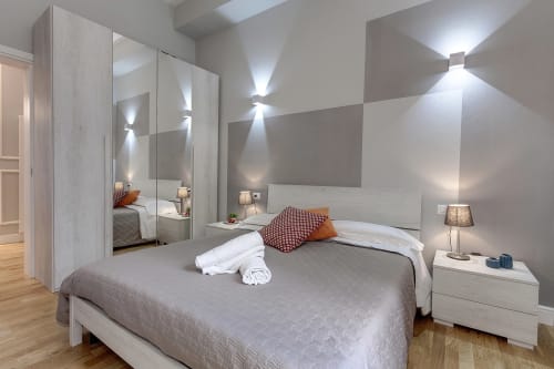 Camera moderna a Sleep tight Florence con letto queen, armadio specchiato, biancheria grigia e illuminazione di accento