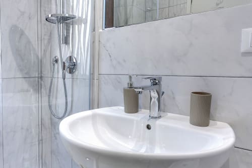 Lavabo moderno con piastrelle di marmo e rubinetto cromato presso l'hotel Sleep tight Florence a Firenze