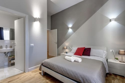 Camera da letto moderna presso Sleep tight Florence con letto matrimoniale, cuscini rossi, bagno ensuite e soffitto inclinato con lucernari