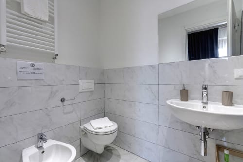 Bagno moderno presso Sleep tight Florence B&B con piastrelle in marmo, lavabo a parete, wc e specchio