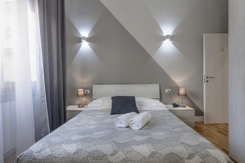 Camera moderna all'hotel Sleep tight Florence con soffitto spiovente, applique murali e asciugamani arrotolati sul letto