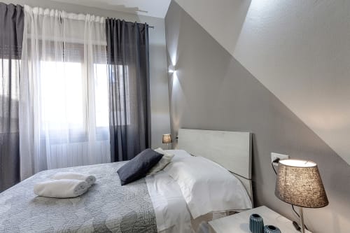 Camera moderna del Sleep tight Florence B&B con letto, tende trasparenti, soffitto spiovente e lampada da comodino