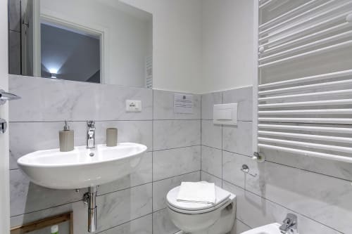 Bagno moderno in Sleep tight Florence con piastrelle di marmo, lavabo bianco, wc, scaldasalviette e zona doccia