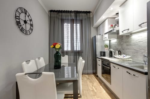 Cucina moderna nella camera Sleep tight Florence B&B con mobili bianchi, tavolo da pranzo e fiori colorati