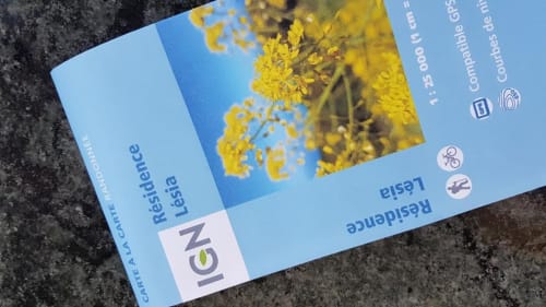 Brochure Résidence Lésia Corbara avec fleurs jaunes et détails de la propriété sur fond bleu