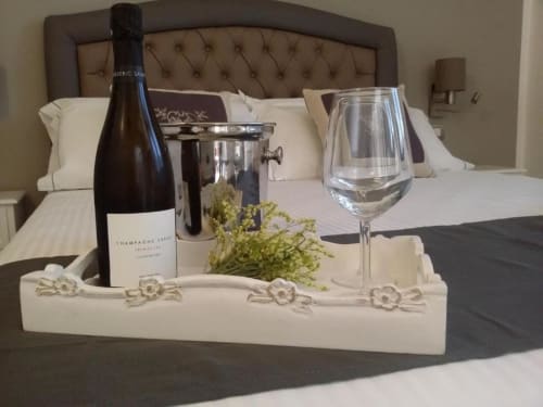Bottiglia di champagne, secchiello del ghiaccio, calice di vino e fiori sul letto del B&B Emozioni Relax a Mantova