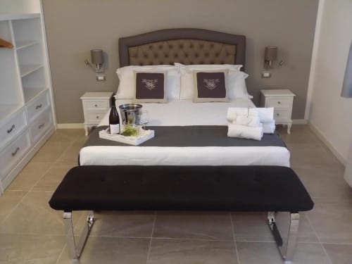 Elegante camera B&B a Emozioni Relax di Mantova con testata imbottita, comodini bianchi e benvenuto con vino