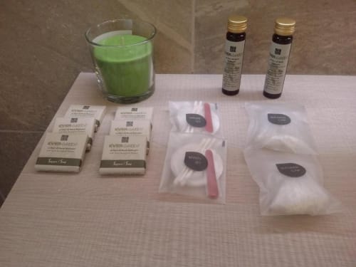 Servizi spa presso B&B Emozioni Relax: candela verde, saponette, oli e prodotti di bellezza su panno bianco