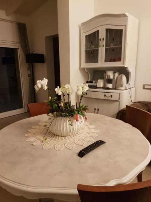 Elegante sala da pranzo del B&B Emozioni Relax con orchidee bianche, tavolo rotondo e credenza vintage a Mantova