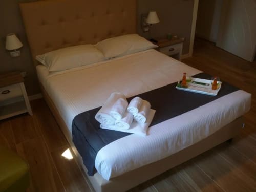 Accogliente camera da letto presso B&B Emozioni Relax a Mantova con asciugamani arrotolati, cuscini e amenità di benvenuto.