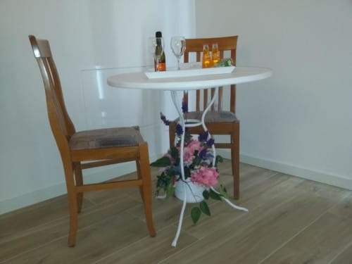 Sala da pranzo del B&B Emozioni Relax con tavolo rotondo, sedie in legno e fiori rosa a Mantova