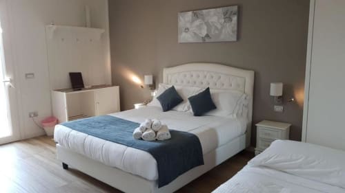 Camera moderna di B&B Emozioni Relax a Mantova con letto bianco, cuscini scuri, asciugamani arrotolati e arredi contemporanei
