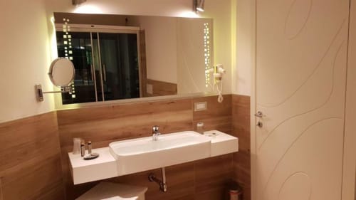 Bagno moderno della B&B Emozioni Relax a Mantova con specchio illuminato, dettagli in legno e lavabo bianco design