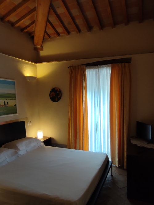 Camera moderna a La Locanda del Vino Nobile a Montepulciano con travi a vista, vista sulla città e tende arancioni