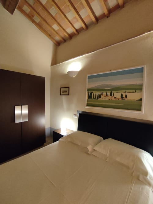 Camera moderna a La Locanda del Vino Nobile con travi a vista, opere d'arte con paesaggi toscani e vedute della città di Montepulciano