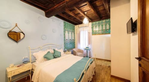 Elegant bedroom at Orso Luxury Apartments Rome with wrought iron bed, green accents, exposed wooden beams, and city view