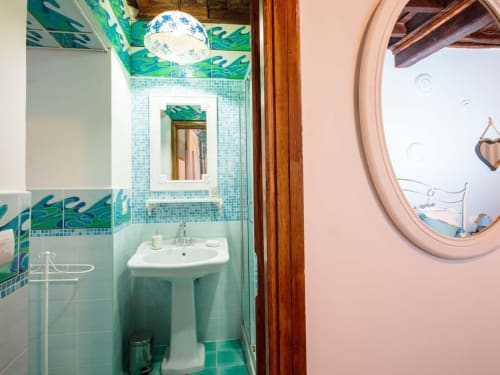 Turquoise-tiled bathroom with pedestal sink and mirror at Orso Luxury Apartments in Roma, Italy