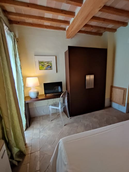 Camera rustica a La Locanda del Vino Nobile a Montepulciano con travi in legno, scrivania e vista sulla città