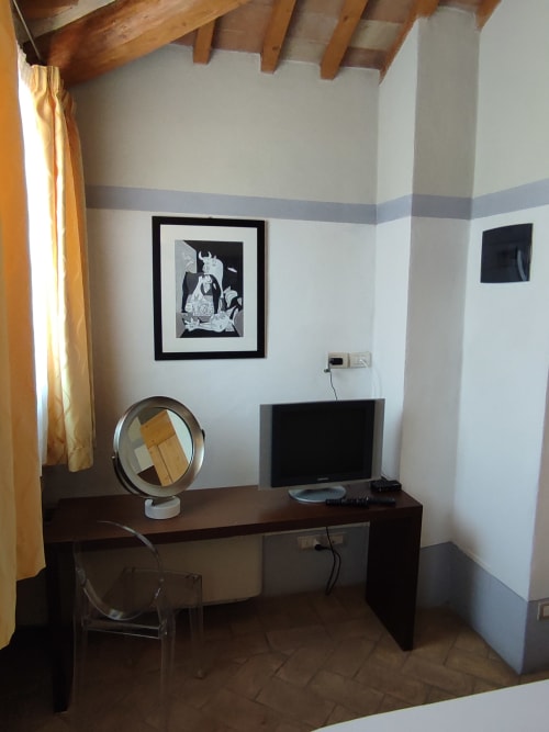 Scrivania dell'hotel nella camera di Montepulciano con monitor, specchio e quadri incorniciati presso La Locanda del Vino Nobile