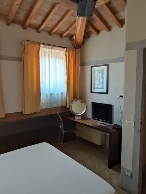 Camera d'albergo a La Locanda del Vino Nobile a Montepulciano con travi a vista, scrivania, TV e finestra con vista sulla città