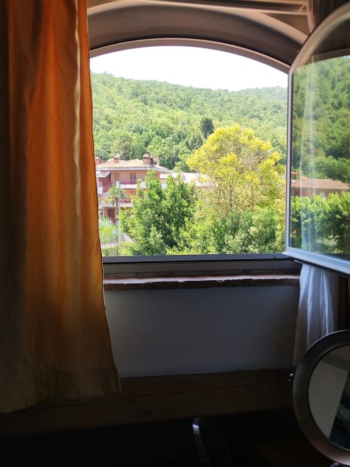 Vista dalla camera di La Locanda del Vino Nobile a Montepulciano: colline boscose e edifici in terracotta