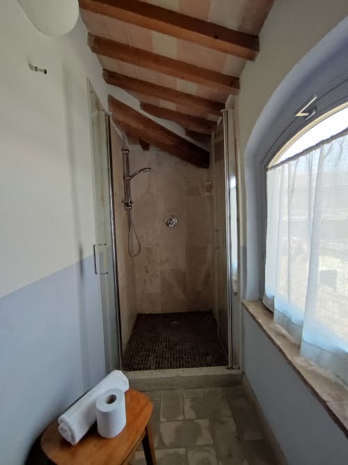 Bagno moderno con doccia a filo pavimento e travi in legno a vista presso La Locanda del Vino Nobile, Montepulciano