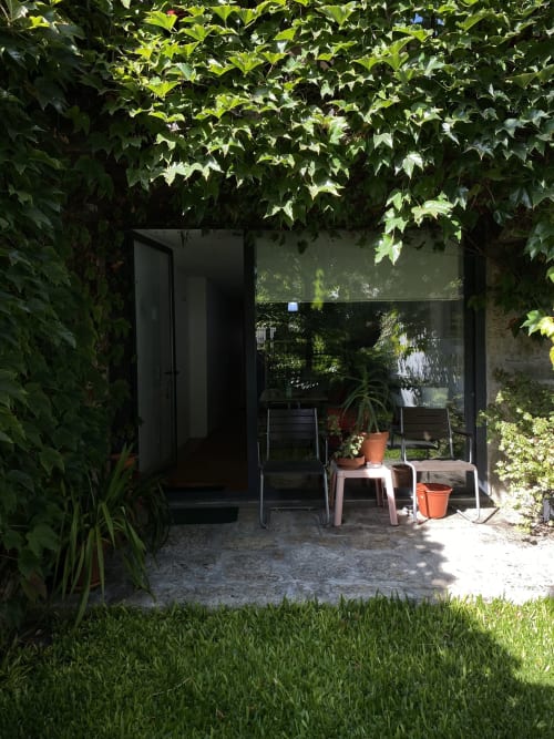 Casa45 Porto garden patio with ivy-covered pergola, seating, and potted plants in afternoon sunlight