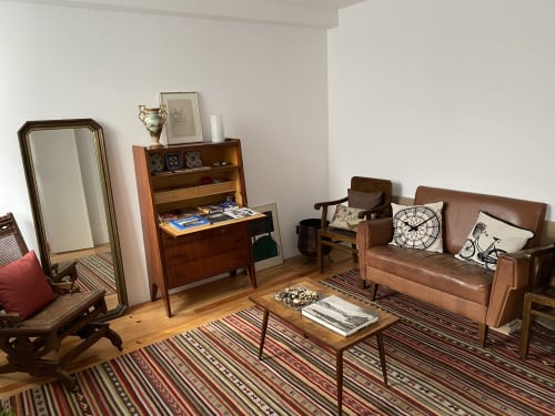 Mid-century living room at Casa45 B&B in Porto with leather sofa, wooden furniture, and striped rug