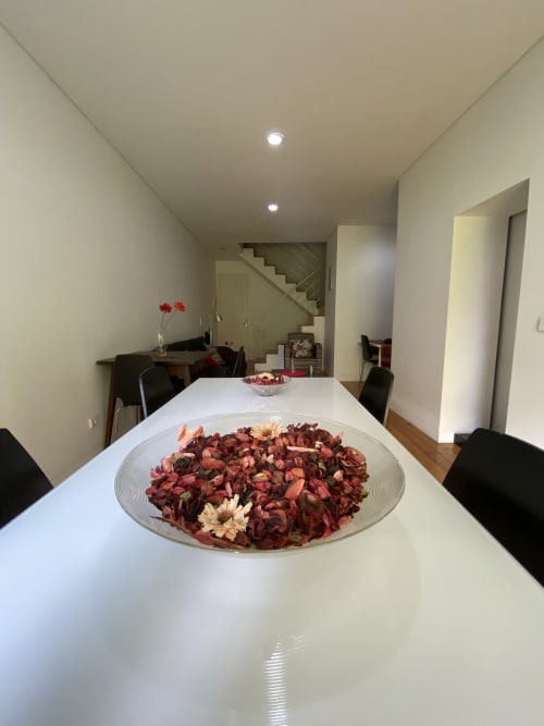 Modern dining room at Casa45 B&B Porto with floral centerpiece, wooden stairs, and minimalist design