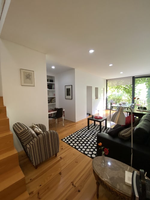Modern living room at Casa45 Porto BnB with striped armchairs, black sofa, wooden floors, and garden views