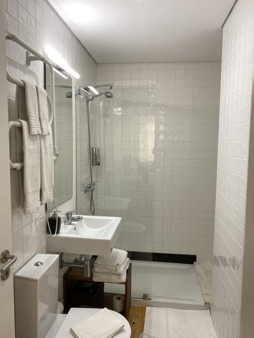 Salle de bains moderne de Casa45 Porto avec carrelage blanc, douche vitrée, lavabo blanc, toilettes et porte-serviettes