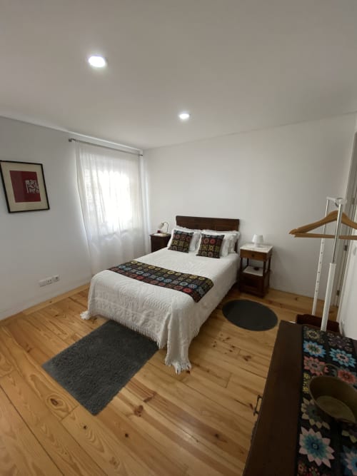 Chambre double lumineuse à Casa45 à Porto avec parquet, literie blanche, mobilier en bois foncé et éclairage encastré.