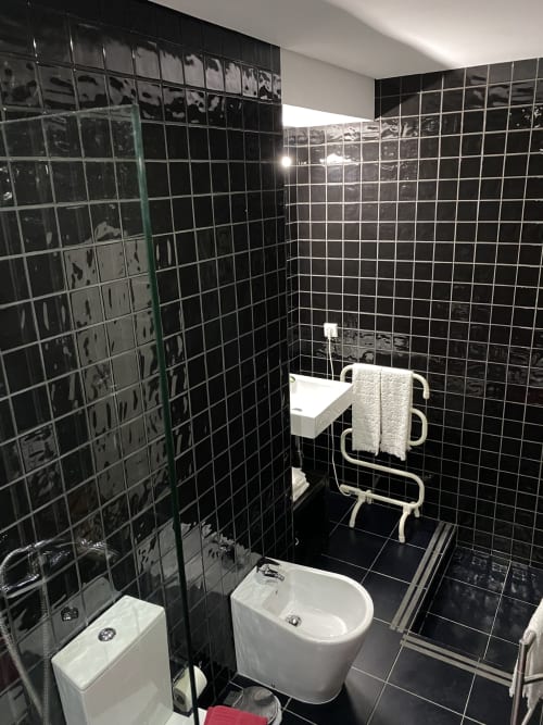 Salle de bain moderne aux carrelages noirs à Casa45 Porto avec lavabo blanc, toilettes, douche et porte-serviettes