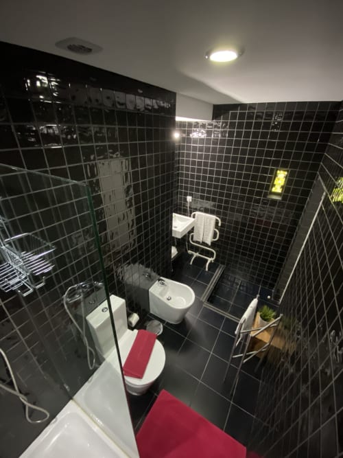 Salle de bain moderne aux carreaux noirs à Casa45 Porto avec toilettes, bidet, douche et tapis de bain rouges