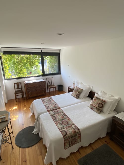 Habitación doble con vista al jardín en Casa45 Porto, con dos camas, muebles de madera y amplias ventanas con vistas a frondosos jardines