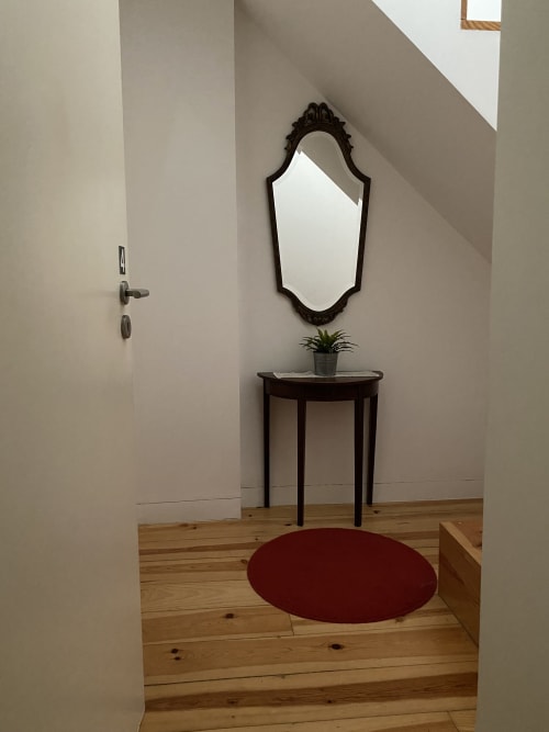 Entrée élégante de Casa45 Porto avec miroir orné, console sombre et tapis circulaire bordeaux sur parquet