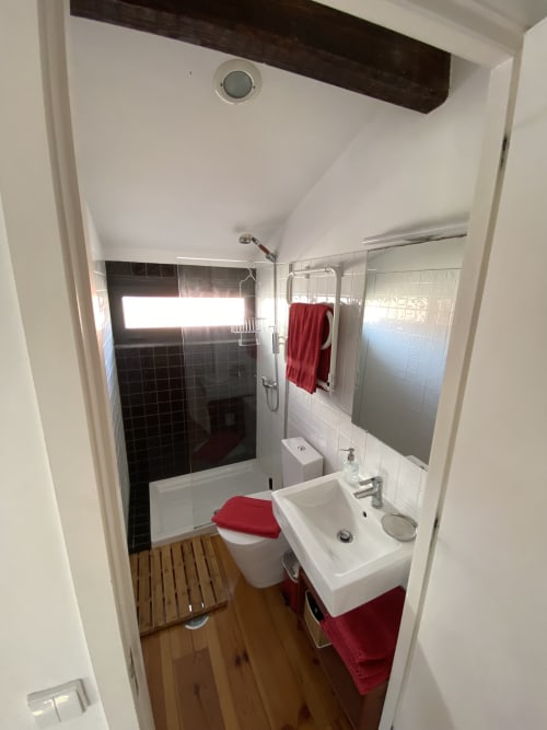 Salle de bain moderne de Casa45 Porto BnB avec lavabo blanc, toilettes, douche, carrelage noir et serviettes rouges