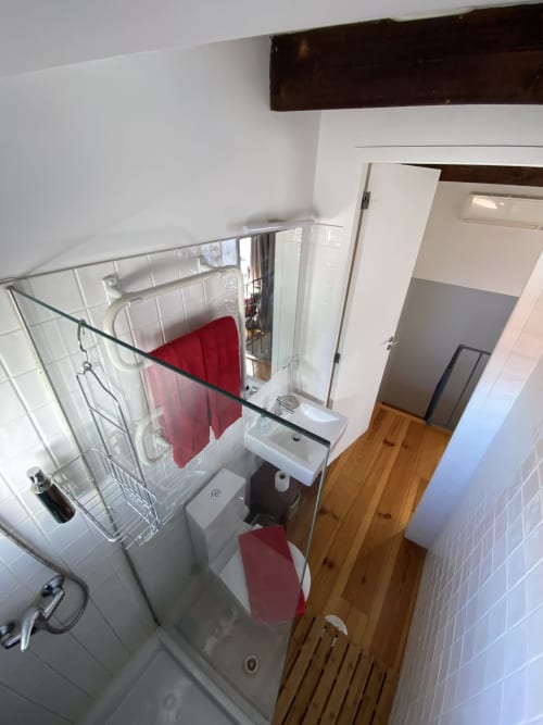 Salle de bain propre à la maison d'hôtes Casa45 Porto avec douche, lavabo et serviettes rouges sur le porte-serviettes