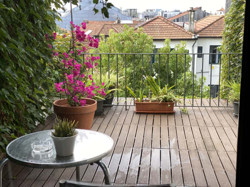 Terrasse de Casa45 Porto avec bougainvillées magenta, terrasse en bois et vues sur la ville aux bâtiments blancs et toits en terre cuite