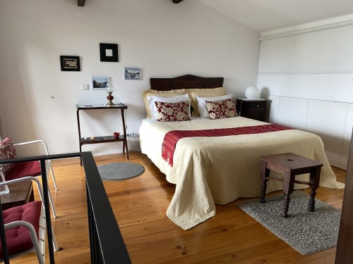 Chambre double lumineuse à Casa45 Porto avec literie crème, mobilier en bois foncé, parquet et vue sur la ville