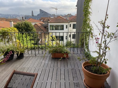 Terrasse Casa45 Porto avec plantes en pots, vue sur les toits et l'horizon de Porto, rampe métallique et terrasse en bois