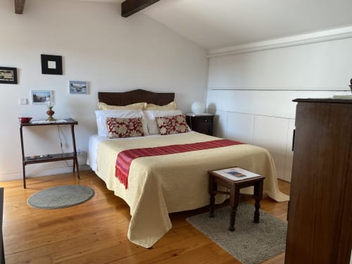 Chambre double spacieuse à Casa45 Porto avec literie crème, accents rouges, mobilier en bois foncé, parquet et vue sur la ville