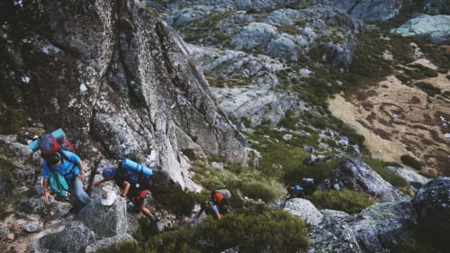 Senderistas escalando el sendero de montaña cerca de Torre Gelbert en Puigcerdà con picos rocosos y vegetación alpina