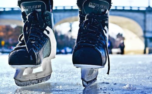 Patines de hielo en blanco y negro sobre superficie congelada con puente y paisaje nevado, Puigcerdà