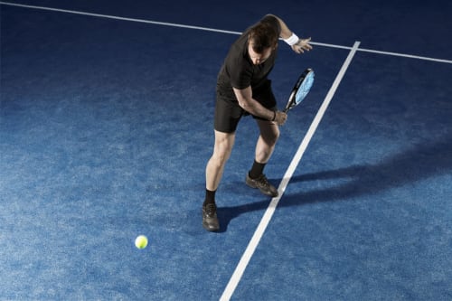 Jugador de tenis sacando en cancha azul del hotel Torre Gelbert en Puigcerdà